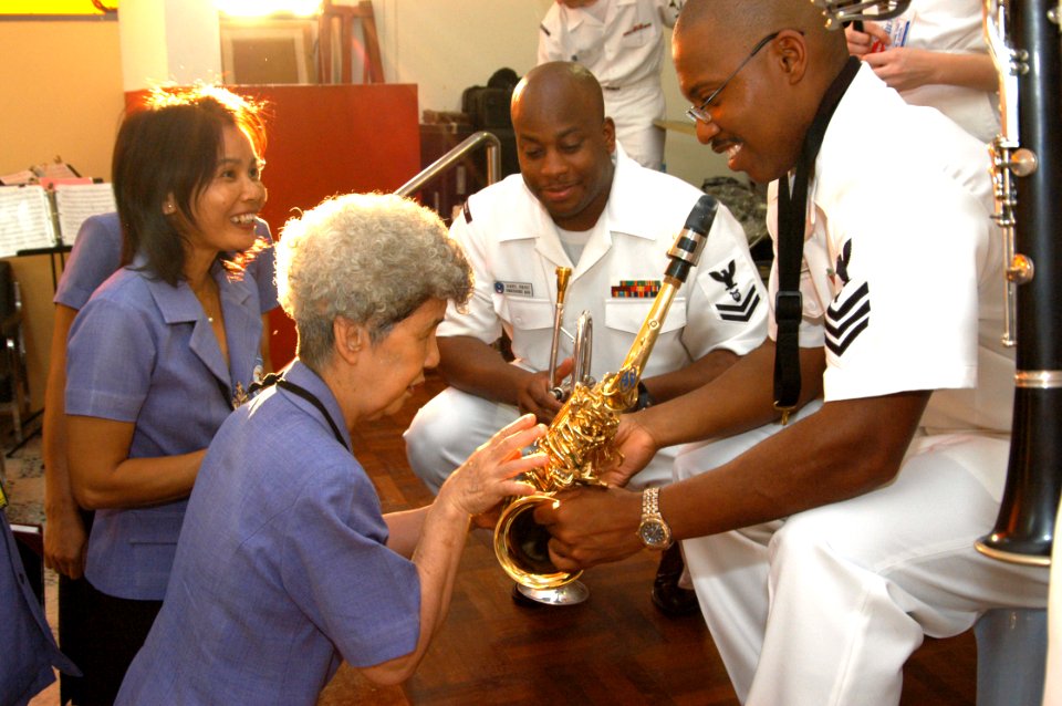 US Navy 060227-N-1194D-009 Seventh Fleet band member Musician 1st Class Frank Newton demonstrates how his saxophone keys operate to Aurora Sribuapun, headmaster of the Pattaya Redemptorist School for the Blind