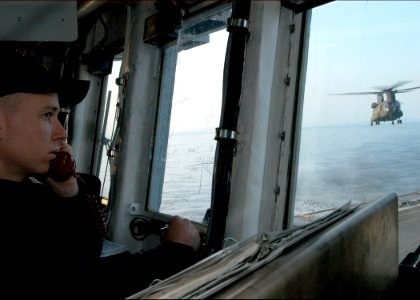 US Navy 060321-N-7526R-126 Lt. j.g. Erik Decker, helicopter control officer (HCL) aboard the amphibious command ship USS Blue Ridge (LCC 19), looks on as an Army CH-47 Chinook helicopter assigned to the 52nd Aviation Regiment C