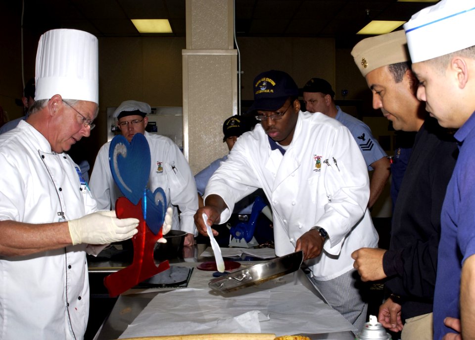 US Navy 060221-N-1126D-006 Mr. David Bearl, left, teaches several culinary specialists the art of working with sugar while they put the final touches on a cake stand
