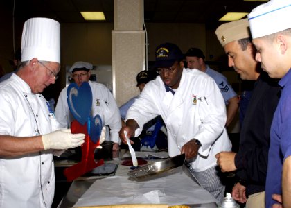 US Navy 060221-N-1126D-006 Mr. David Bearl, left, teaches several culinary specialists the art of working with sugar while they put the final touches on a cake stand