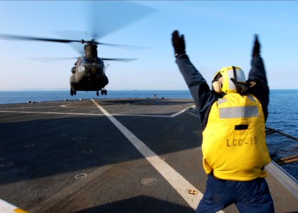 US Navy 060321-N-7526R-041 Boatswain's Mate 2nd Class Edgardo Bauzon signals to an Army CH-47 Chinook helicopter assigned to the 52nd Aviation Regiment Camp from Humphreys Korea