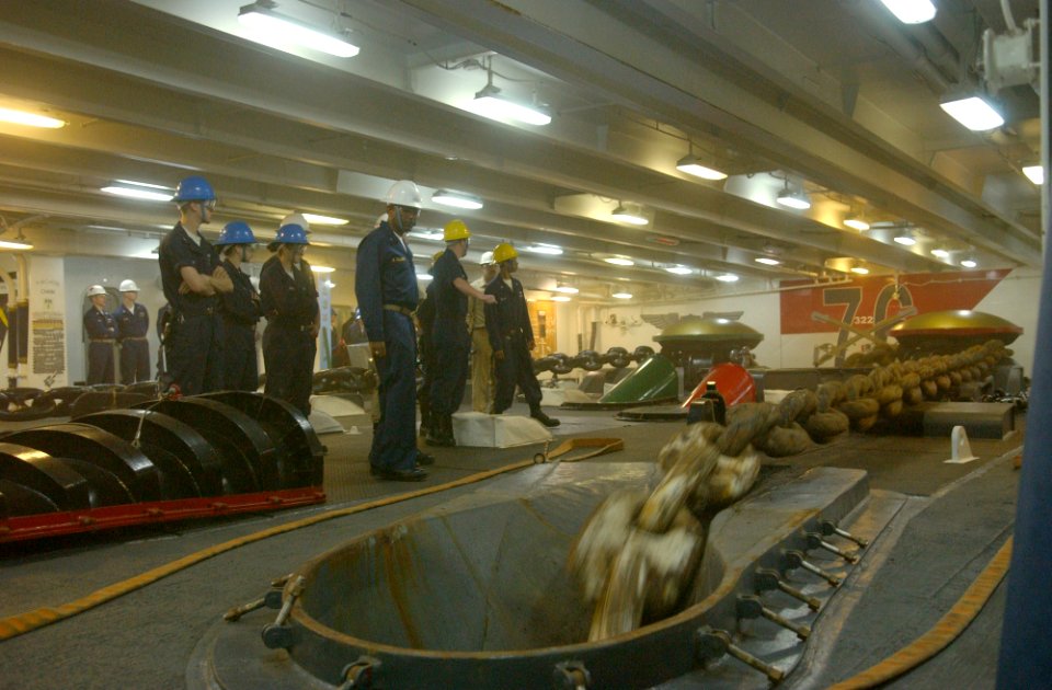 US Navy 060325-N-4776G-231 Boatswain's Mates stand clear as the hydraulic brake is released and the anchor and chain trail down to the bottom of the Persian Gulf