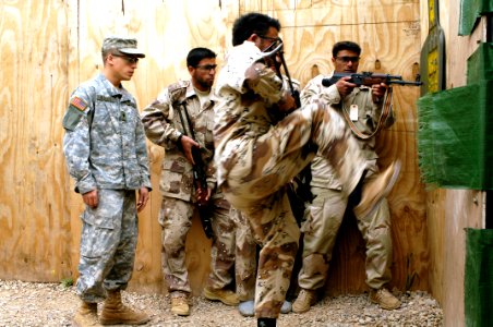 US Navy 060412-N-4614W-018 An Iraq Army soldier, from 5th Battalion, kicks in a door, inside the kill house, as Army Spc. Nate Wagar, assigned to Headquarters Company, 1st Battalion, 327th Infantry Regiment observes