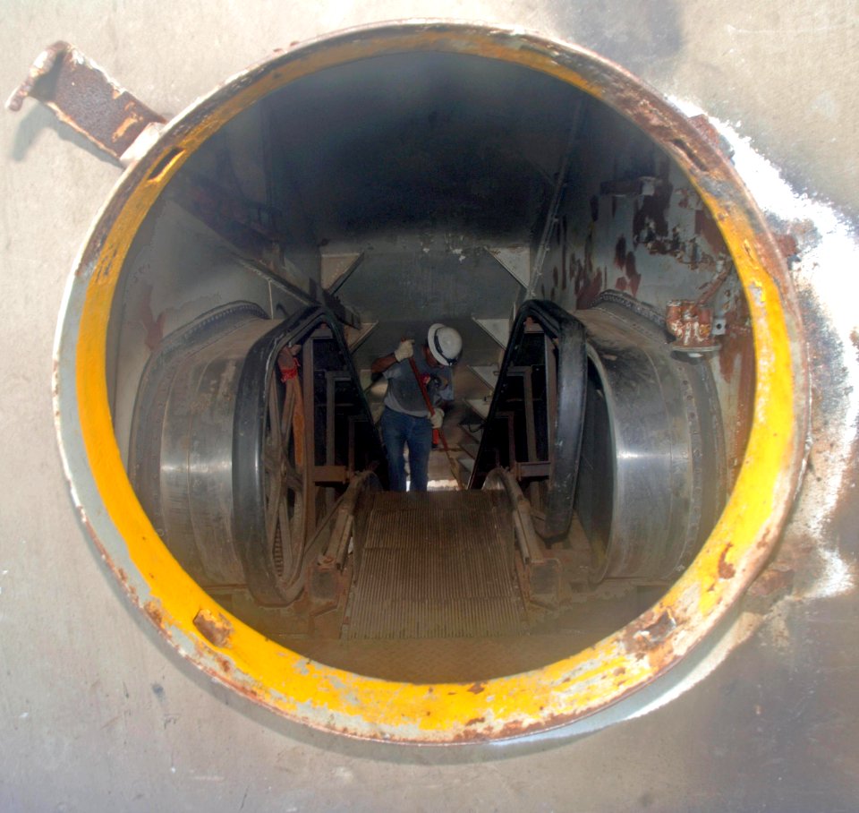 US Navy 060419-N-4097B-002 Resolve Marine Group employee, Robert Luna sweeps dust and debris from the escalator aboard the decommissioned aircraft carrier USS Oriskany (CVA 34)
