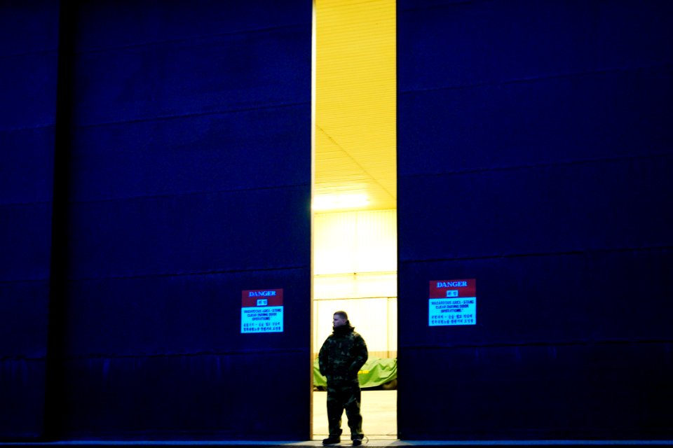 US Navy 060329-N-6074Y-022 Aviation Electronics Technician Airman Shane Pfannestiel, assigned to Helicopter Anti-Submarine Squadron Two (HS-2) Golden Falcons, stands at the door of an aircraft hangar