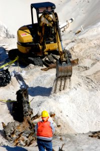 US Navy 060324-5328N-N-207 Using a mini excavator, a heavy equipment operator with the Pittsburgh, Pa.-based, Dick Corp. carefully covers the remains of a wrecked wooden ship aboard Naval Air Station Pensacola