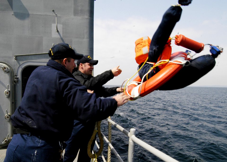 US Navy 060406-N-2385R-215 Boatswain's Mates 2nd Class John George, left, and Corey S. Masterson, right, throw a man overboard simulation device into the water