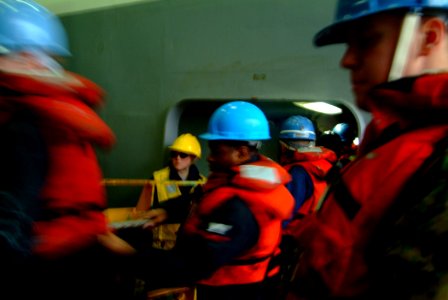 US Navy 060401-N-4772B-039 Seaman Kimberly Tozier (center in yellow) supervises line handlers aboard the amphibious dock landing ship USS Harpers Ferry (LSD 49), during an underway replenishment (UNREP)