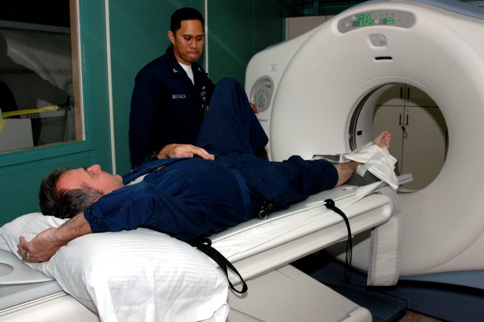 US Navy 060501-N-2832L-001 Hospital Corpsman 3rd Class Ronald Bayaca a computerized tomography (CT) scan technician, checks the lower-right extremity of a sailor aboard the Military Sealift Command hospital ship USNS Mercy (T-A