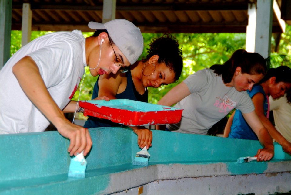 US Navy 060525-N-4772B-071 Crew members assigned to the amphibious dock landing ship USS Harpers Ferry (LSD 49) paint the stage near the cafeteria of a local school during a Community Relations (COMREL) project