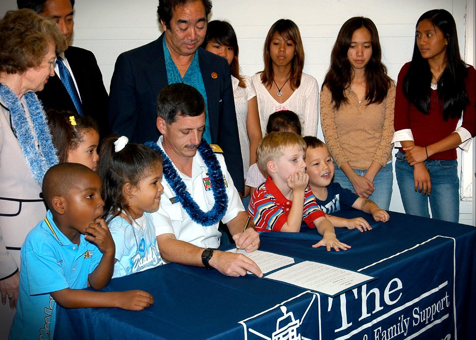 US Navy 060410-N-4856G-114 State Representatives, Fleet and Family Support Personnel (FFSP), and Navy family members watch as Commander Navy Region Hawaii, Adm. Michael Vitale signs a proclamation