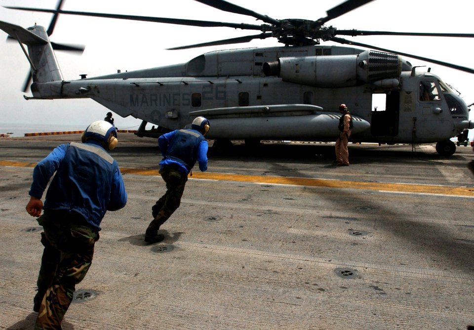 US Navy 060430-N-9866B-010 Flight deck personnel run toward a CH-53Super Stallion helicopter to remove the chalks and chains before it takes off from the flight deck