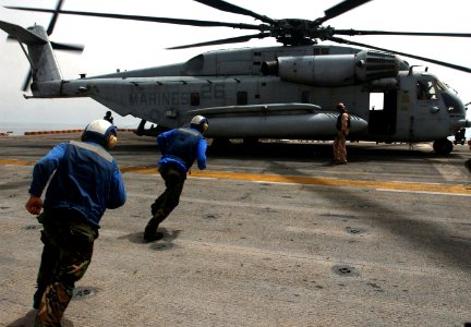 US Navy 060430-N-9866B-010 Flight deck personnel run toward a CH-53Super Stallion helicopter to remove the chalks and chains before it takes off from the flight deck