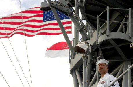 US Navy 060529-N-9851B-005 Personnel Specialist 1st Class Aldwin Camuro mans the rails aboard the amphibious dock landing ship USS Tortuga (LSD 46) as she pulls into Changi Naval Base, Singapore