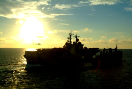 US Navy 060530-N-4772B-066 A helicopter hovers over the flight deck of the amphibious assault ship USS Essex (LHD 2) during an underway replenishment