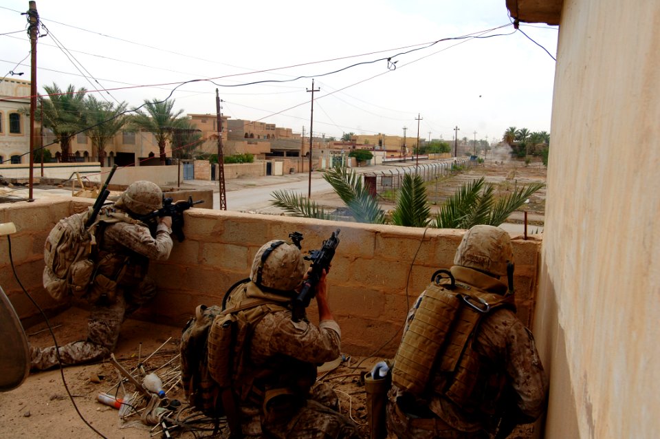 US Navy 060520-N-7497P-229 Cpl. Julius Mitchell, left, and Cpl. Jeremy Rugg, center, lay down covering fire while Cpl. Adam Gokey spots insurgent positions on his right and fires a grenade, seen traveling through the air, whil