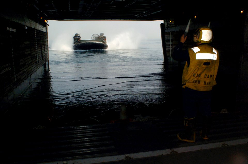US Navy 060421-N-9866B-006 Seaman Sergio Segura directs Landing Craft, Air Cushion Seven Two (LCAC 72) into the well deck of the amphibious assault ship USS Peleliu (LHA 5)