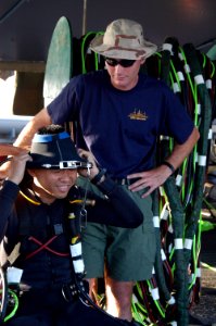 US Navy 060606-N-4205W-012 Gunner's Mate 3rd Class Brian Huffman watches Maj. Yip Wai Choong from the Republic of Singapore Navy (RSN) don the neck dam prior to diving in the water