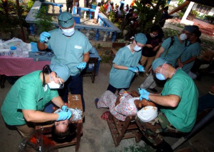 US Navy 060528-N-8391L-462 U.S. Navy Dentist Cmdr. Jan DeLorey-Lytle, left and Air Force Dentist Lt. Col. Gary Leake, right, work side-by-side performing tooth extractions during a dental assistance mission photo