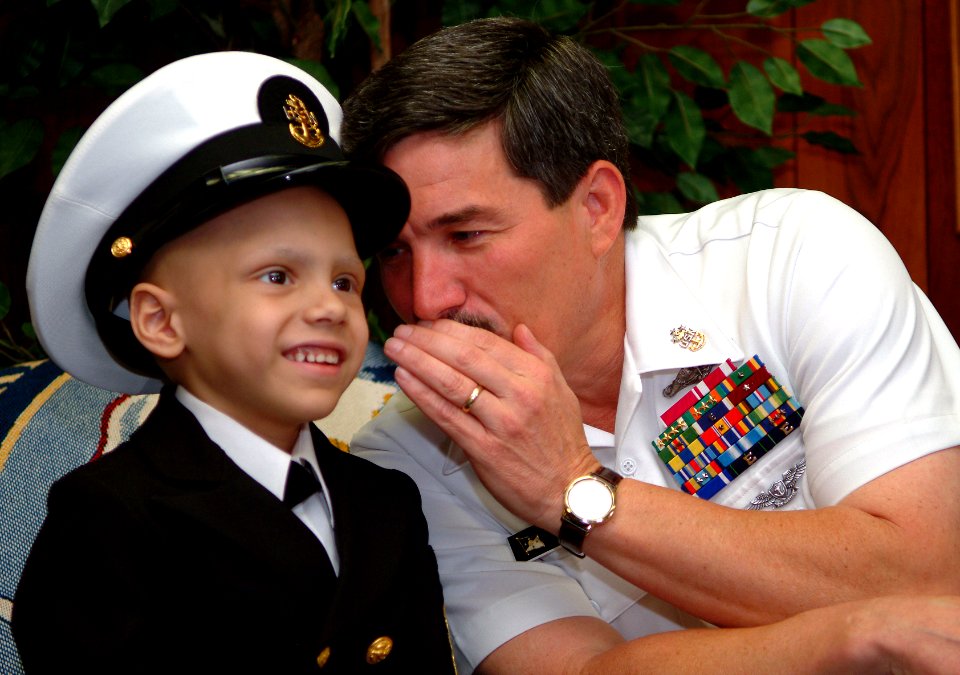 US Navy 060602-N-0962S-053 Master Chief Petty Officer of the Navy (MCPON) Terry Scott exchanges a few secrets between chiefs with seven-year-old Honorary Chief Hospital Corpsman Diego Santiago