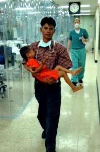 US Navy 060529-N-2832L-012 A man carries his son from the intensive care unit aboard the U.S. Military Sealift Command (MSC) hospital ship USNS Mercy (T-AH 19) photo