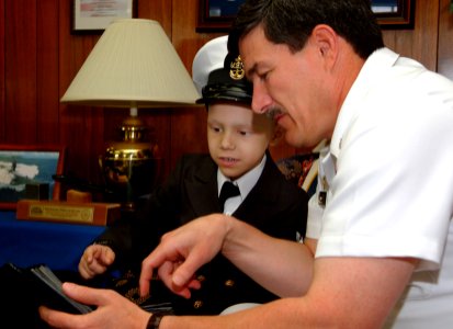 US Navy 060602-N-0962S-058 Master Chief Petty Officer of the Navy (MCPON) Terry Scott flips through a photo album with seven-year-old Honorary Chief Hospital Corpsman (FMF) Diego Santiago