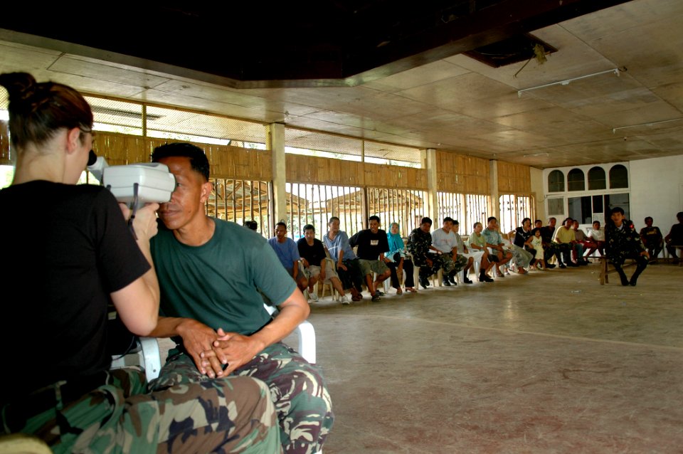 US Navy 060606-N-3714J-052 Air Force Capt. Jennifer Owen of Birmingham, Ala., conducts an eye exam, while others wait in line to be seen for glasses at Camp Batista