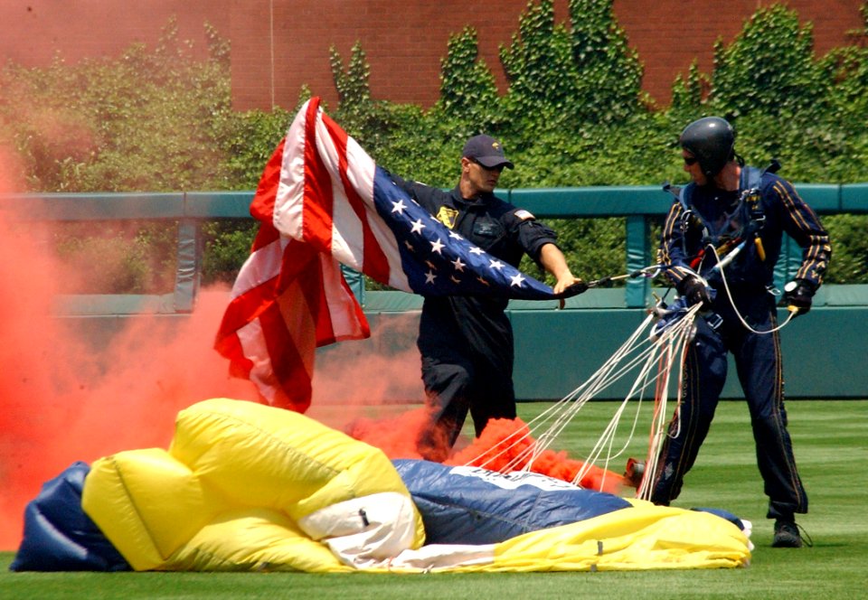 US Navy 060618-N-4729H-096 A member of the Navy Parachute Team Leapfrogs unhooks the American flag from the Team Officer in Charge, Lt. Geoff Reeves, after his jump in to Citizens Bank Park