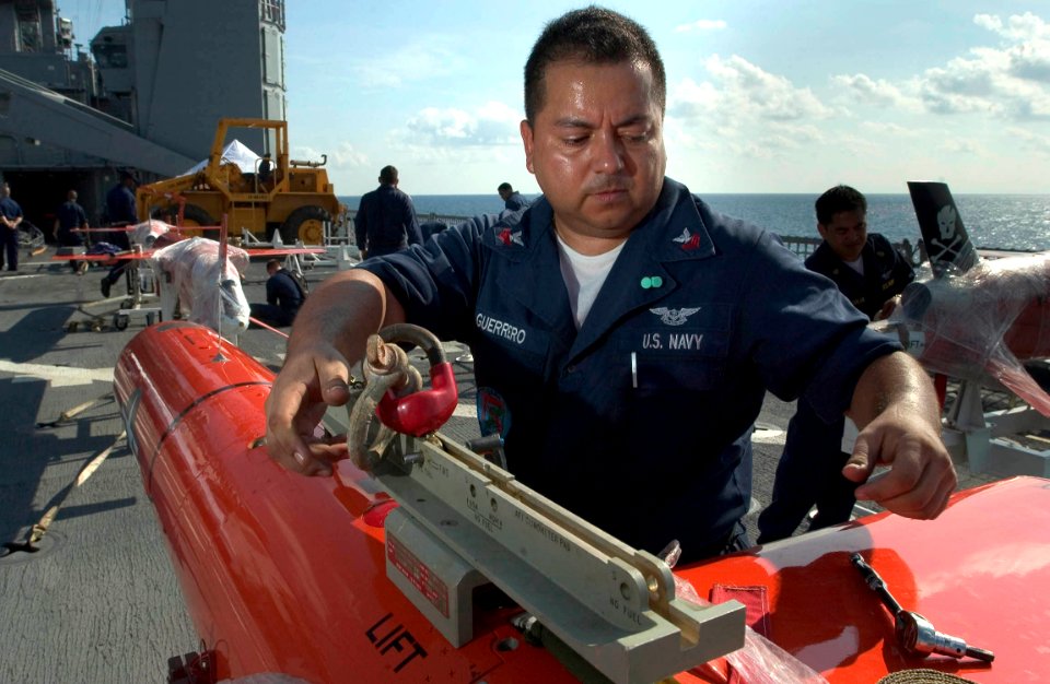 US Navy 060607-N-9851B-013 Aviation Structural Mechanic 1st Class Tony Guerrero assigned to Commander, Fleet Activities Okinawa Drone Detachment, attaches an eye to connect a BQM-74E aerial target to a crane aboard USS Tortuga