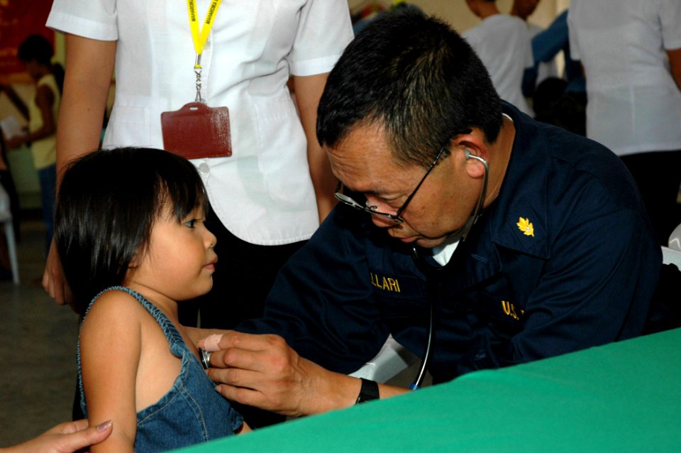 US Navy 060611-N-1577S-112 Navy Cmdr. Jesus Mallari assigned to the U.S. Military Sealift Command (MSC) Hospital Ship USNS Mercy (T-AH 19), examines a patient