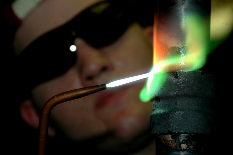 US Navy 060528-N-1332Y-022 Hull Maintenance Technician Fireman Bob Chambers uses a brazing torch to weld a one-and-a-half-inch copper-nickel pipe in the pipe shop aboard USS Kitty Hawk (CV 63)