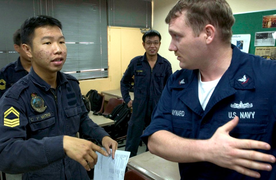 US Navy 060531-N-9851B-001 Damage control team leaders, Republic of Singapore Navy (RSN) 1st Sgt. Choon Wye Wong and Damage Controlman 3rd Class Chris Maynard discuss how they will divide participants in a combined damage contr