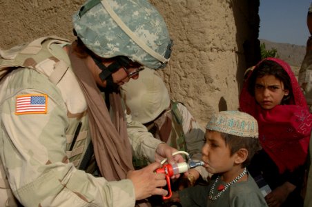US Navy 060612-A-5679R-008 U.S. Navy Petty Officer 1st Class Michele Reed, assigned to the 405th Civil Affairs Battalion, gives a young Afghan boy a deworming solution photo