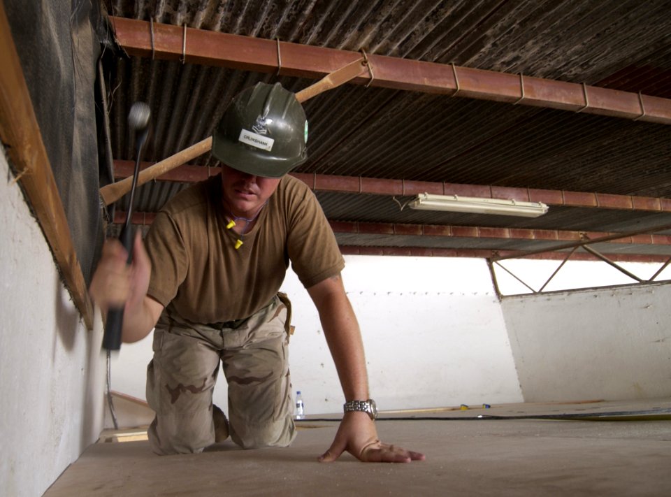 US Navy 060614-N-0411D-103 U.S. Navy Utilitiesman 2nd Class Richard Cruikshank, assigned to Naval Mobile Construction Battalion Seven (NMCB-7), hammers the last section of ceiling plywood