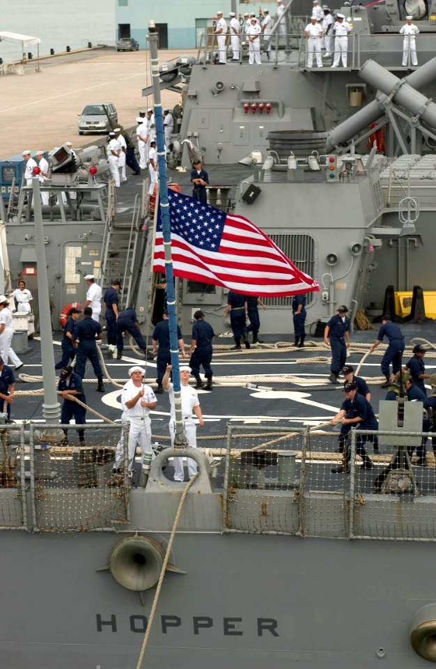 US Navy 060614-N-9851B-003 Sailors aboard Arleigh Burke-class guided missile destroyer USS Hopper (DDG 70) lower the American Flag on the ship's fantail as Hopper shifts colors for getting underway