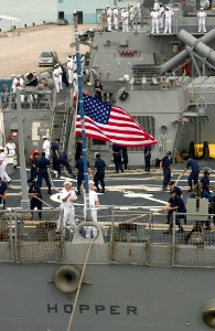 US Navy 060614-N-9851B-003 Sailors aboard Arleigh Burke-class guided missile destroyer USS Hopper (DDG 70) lower the American Flag on the ship's fantail as Hopper shifts colors for getting underway