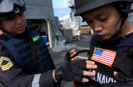 US Navy 060606-N-9851B-015 1st Sgt. Louis Goh and Personnel Specialist 2nd Class Tristan Delatorre, members of a combined U.S. and RSN visit, board, search and seizure (VBSS) team, compare equipment on the deck of amphibious do