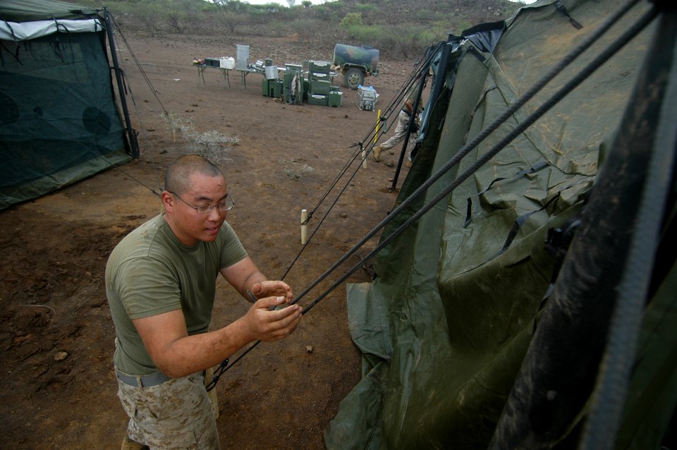US Navy 060804-N-0411D-026 U.S. Marine Lance Cpl. Simon Lin of Chino Hills, Calif., tightens up a corner rope while setting up the command tent at Camp Lonestar