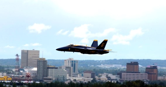 US Navy 060812-F-7049H-007 An F-18 Super Hornet belonging to the Blue Angels speeds past an Anchorage skyline during Arctic Thunder 2006