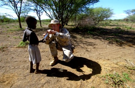 US Navy 060811-N-0411D-027 U.S. Marine Staff Sgt. Jesse Peters helps a local Pokot tribe boy to open a portion of a military food ration (MRE) given to him by a U.S. service member