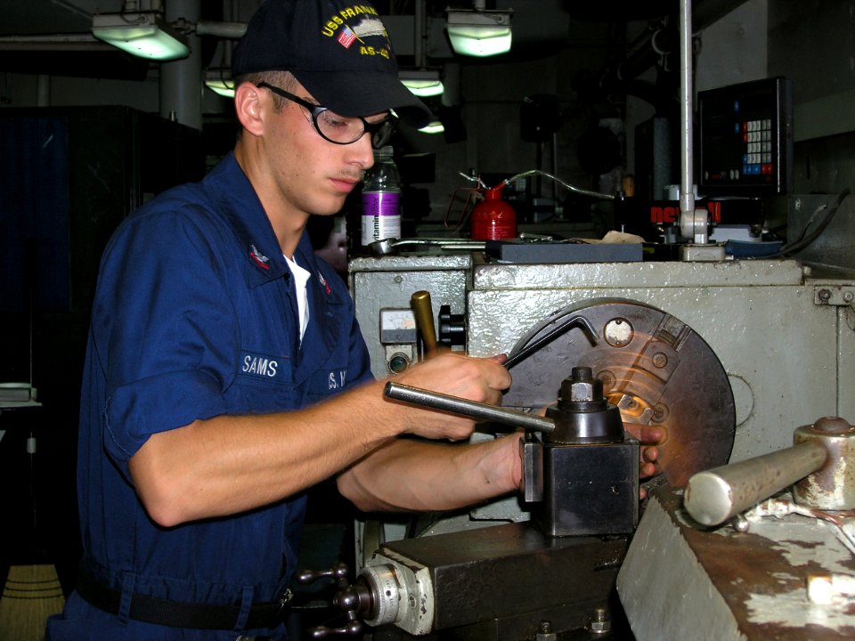 US Navy 060615-N-0000X-001 Machinery Repairman 2nd Class Evan Sams uses a milling machine to make a part for a submarine while in the machine repair shop aboard the submarine tender USS Frank Cable (AS 40)