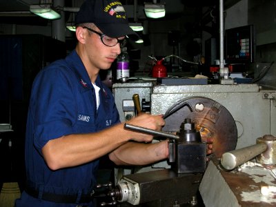 US Navy 060615-N-0000X-001 Machinery Repairman 2nd Class Evan Sams uses a milling machine to make a part for a submarine while in the machine repair shop aboard the submarine tender USS Frank Cable (AS 40)