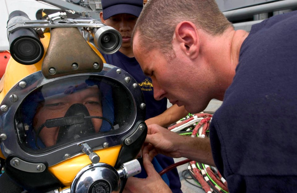 US Navy 060621-N-9851B-002 Royal Thai Navy diver Ensign Mongkol Boontun has a MK-21 diving helmet fastened by Gunner's Mate 3rd Class Bryan Huffman during a MK-21 familiarization dive