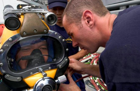 US Navy 060621-N-9851B-002 Royal Thai Navy diver Ensign Mongkol Boontun has a MK-21 diving helmet fastened by Gunner's Mate 3rd Class Bryan Huffman during a MK-21 familiarization dive