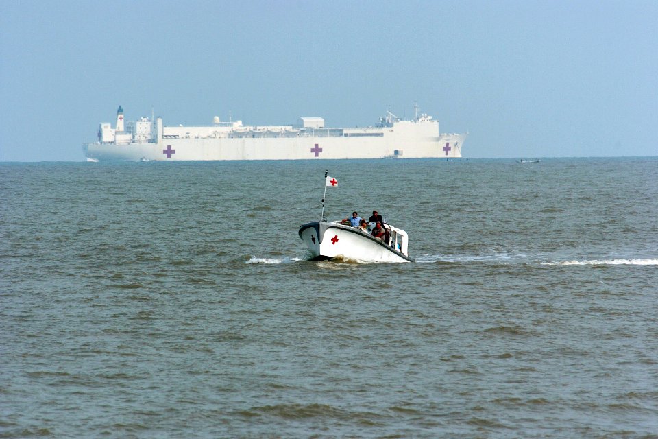 US Navy 060814-N-6501M-123 The Military Sealift Command (MSC) hospital ship USNS Mercy (T-AH 19) sits on the horizon as Band-Aid One, one of two transport boats shuttle patients and crew from ship to shore