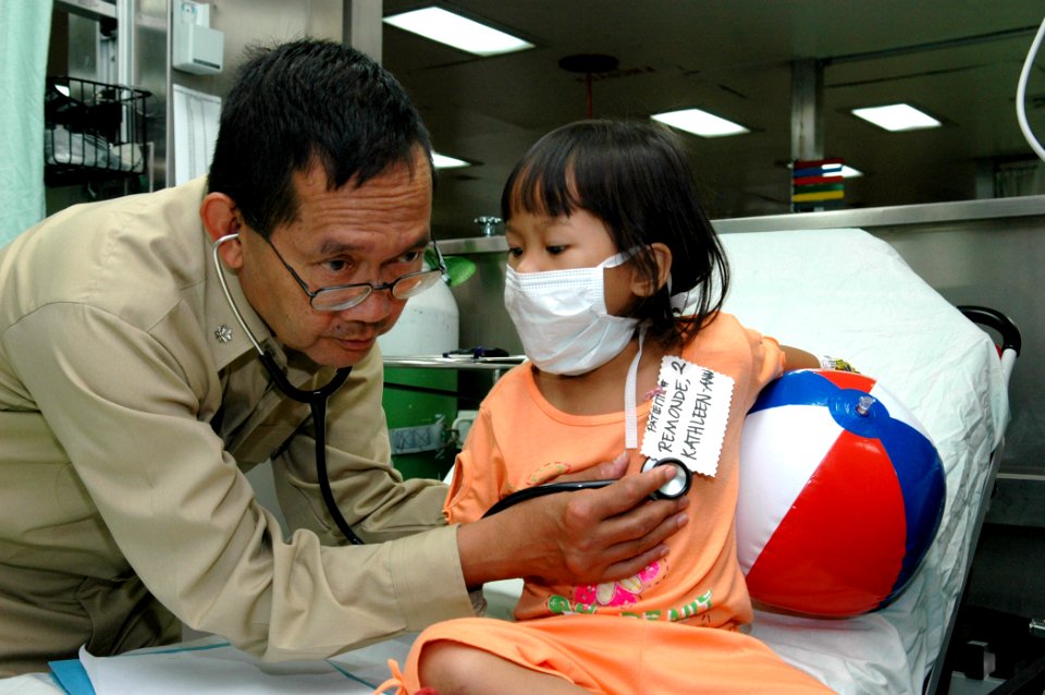 US Navy 060613-N-3714J-015 Navy Cmdr. Jesus Mallari, a Philippine native, listens to a child's heartbeat while getting her vital signs
