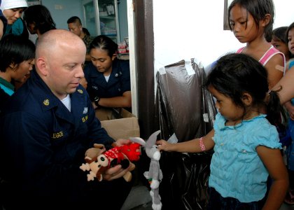 US Navy 060816-N-3714J-094 Navy Chief Hospital Corpsman Chris Gallegos of San Diego, a member the Medical Treatment Facility aboard the U.S. Naval hospital ship USNS Mercy (T-AH 19), distributes stuffed animals to children