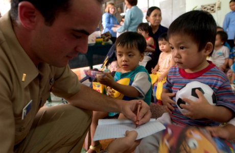 US Navy 060703-N-9851B-006 Ensign James Zumwalt, assigned to the rescue and salvage ship USS Salvor (ARS 52), uses a crayon to make a drawing for a child living in Thien Binh Orphanage