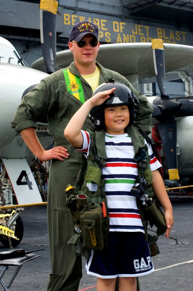 US Navy 060702-N-9864S-030 Lt. Chris Swanson assigned to Carrier Airborne Early Warning One One Five (VAW-115) poses with a young Japanese boy, whom he lent his helmet and flight gear