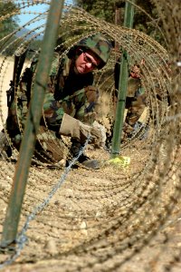 US Navy 060817-N-0775Y-009 Builder Constructionmen Aaron Stokes stretches barbed wire through a spool of Concertina wire to secure an entry point at the camps Logistics Support Area (LSA)